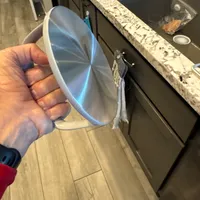 Customer-uploaded image. Click to see more details. The image represents: A hand holding a clear glass bowl in a kitchen with granite countertops and dark cabinets