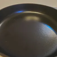 Customer-uploaded image. Click to see more details. The image represents: A dark non-stick frying pan or skillet sitting on a white surface in a kitchen