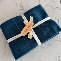 Customer-uploaded image. Click to see more details. The image represents: A bundle of dark blue fabric napkins tied with cream-colored ribbon and an orange Caraway brand tag, placed on a marble surface