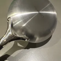 Customer-uploaded image. Click to see more details. The image represents: Stainless steel frying pan viewed from above showing circular brushed metal surface and handle