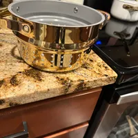 Customer-uploaded image. Click to see more details. The image represents: A gold-colored double boiler or steamer pot with perforated bottom section sitting on a granite kitchen countertop