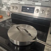 Customer-uploaded image. Click to see more details. The image represents: Stainless steel skillet with lid sitting on black glass-top electric stove in modern kitchen with tile backsplash