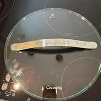 Customer-uploaded image. Click to see more details. The image represents: Glass lid on black induction cooktop with Caraway brand label and control panel visible