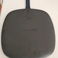 Customer-uploaded image. Click to see more details. The image represents: A dark colored square-shaped frying pan with rounded corners and a long handle, with "Caraway" brand name embossed on the cooking surface