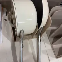 Customer-uploaded image. Click to see more details. The image represents: A white and black headphone displayed on a stand with chrome handles in what appears to be a retail or showroom setting.