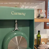 Customer-uploaded image. Click to see more details. The image represents: A green Caraway cookware box displaying a 4.5-qt saute pan is shown on a kitchen counter. Above it is a promotional message offering 10% off with code EASTCOASTEM. The counter features wooden shelves with decorative items and kitchen accessories.