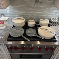 Customer-uploaded image. Click to see more details. The image represents: A modern kitchen stovetop with multiple pots and pans with lids arranged on the burners, featuring stainless steel appliances, granite countertops, and a decorative tile backsplash
