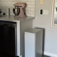 Customer-uploaded image. Click to see more details. The image represents: Kitchen corner with pink stand mixer on white countertop, white subway tile backsplash, stainless steel trash can, and partial view of black dishwasher
