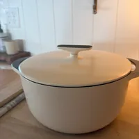 Customer-uploaded image. Click to see more details. The image represents: White ceramic Dutch oven with lid on wooden kitchen counter