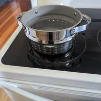 Customer-uploaded image. Click to see more details. The image represents: A stainless steel steamer basket sitting on a stovetop burner in a modern kitchen