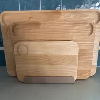 Customer-uploaded image. Click to see more details. The image represents: Three wooden cutting boards of different sizes stacked against blue tile backsplash on kitchen counter
