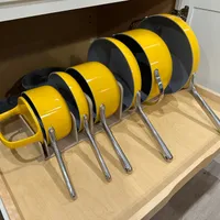 Customer-uploaded image. Click to see more details. The image represents: A set of yellow and black pots and pans with metal handles organized in a pull-out kitchen drawer organizer