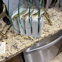 Customer-uploaded image. Click to see more details. The image represents: Kitchen counter with organized cookware storage rack holding glass lids and pans on granite countertop