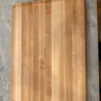 Customer-uploaded image. Click to see more details. The image represents: A rectangular wooden cutting board with visible wood grain patterns sitting on a marble countertop surface