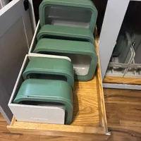 Customer-uploaded image. Click to see more details. The image represents: A wooden drawer containing four stacked green and gray storage containers with handles, organized neatly inside a white fabric-lined compartment.