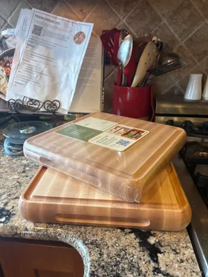 Customer-uploaded image. Click to see more details. The image represents: Two wooden cutting boards stacked on a granite kitchen counter, with kitchen utensils in a red container and recipe papers visible in the background