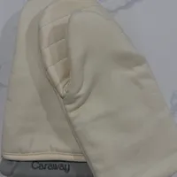 Customer-uploaded image. Click to see more details. The image represents: A beige colored travel pillow with "Caraway" branding lying on white bedding