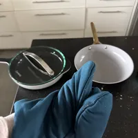 Customer-uploaded image. Click to see more details. The image represents: Person wearing blue cleaning gloves holding a cloth while cleaning cookware on a kitchen counter