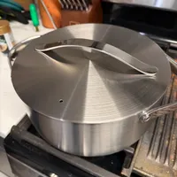 Customer-uploaded image. Click to see more details. The image represents: A stainless steel pot with lid and handles sitting on a gas stovetop in a kitchen