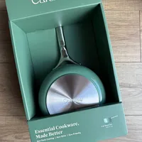 Customer-uploaded image. Click to see more details. The image represents: Caraway brand non-stick sauce pan with lid in sage green color displayed in its packaging box on a wooden surface