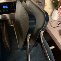 Customer-uploaded image. Click to see more details. The image represents: Two large frying pans with long handles drying on a blue kitchen towel next to a microwave and stove