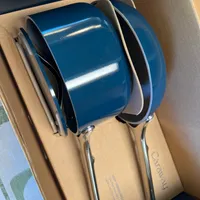 Customer-uploaded image. Click to see more details. The image represents: Blue enameled cookware set with stainless steel handles displayed in a cardboard box with packaging materials.