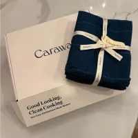 Customer-uploaded image. Click to see more details. The image represents: Caraway brand cookware packaging with navy blue kitchen towels tied with ribbon on white box labeled "Good Looking, Clean Cooking"