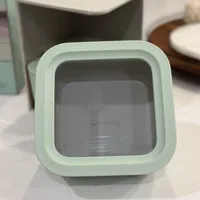 Customer-uploaded image. Click to see more details. The image represents: A mint green smart home device with a square display screen sitting on a white surface, with other home accessories blurred in the background.