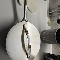 Customer-uploaded image. Click to see more details. The image represents: A stainless steel frying pan with lid sits on a white stovetop in a modern kitchen