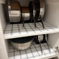 Customer-uploaded image. Click to see more details. The image represents: Kitchen cabinet with organized cookware storage showing pots and pans with handles neatly arranged on two shelves lined with checkered shelf paper