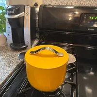 Customer-uploaded image. Click to see more details. The image represents: Orange pot with lid and handles sitting on black stovetop in kitchen with Keurig coffee maker and microwave visible in background