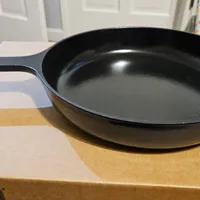 Customer-uploaded image. Click to see more details. The image represents: A black cast iron skillet sitting on a wooden cutting board in a kitchen