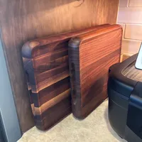 Customer-uploaded image. Click to see more details. The image represents: Two wooden cutting boards stored vertically in a kitchen cabinet above a marble countertop