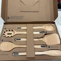 Customer-uploaded image. Click to see more details. The image represents: An open cardboard box containing a set of FSC-certified wooden kitchen utensils including a spoon, server, spatula, scraper, and tongs, each labeled with numbers and the Caraway brand name. The box features the tagline "Ready, set, prep" and the Instagram handle @caraway_home at the top.