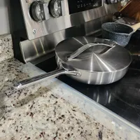 Customer-uploaded image. Click to see more details. The image represents: A stainless steel LG electric stove with two burners on the left, digital controls in the center, and two knobs on the right. A large skillet with lid sits on the stovetop. The stove is positioned on a speckled granite countertop in a kitchen.