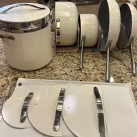 Customer-uploaded image. Click to see more details. The image represents: Kitchen counter displaying white cookware including a large pot with lid, plates in a drying rack, and cutting boards with handles laid out on granite countertop