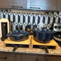 Customer-uploaded image. Click to see more details. The image represents: Kitchen counter with two dark blue Dutch ovens sitting on wooden trivets, featuring geometric patterned backsplash and stainless steel cabinets