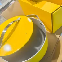 Customer-uploaded image. Click to see more details. The image represents: Yellow cookware pot with lid and handles next to yellow product boxes on a counter