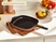 Caraway perracotta enameled cast iron grill pan with a ridged black interior on a counter.
