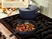 Caraway navy enameled cast iron skillet cooking vegetables beside a lidded Dutch oven.