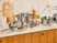 Three glass lids with silver-tone handles fitted to stainless steel cookware on a counter.