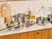 Three glass lids with gold-tone handles fitted to stainless steel cookware on a counter.