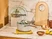 Caraway lid organizer holding glass lids beside Gray cookware on a counter.