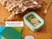 Caraway sage mini rectangle container holding sandwich wraps and grapes beside a bag and books.