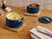 Caraway navy ceramic sauce pans holding mashed potatoes and roasted vegetables on woven trivets.
