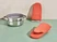 Caraway perracotta oven mitts beside a stainless steel steamer.
