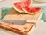 Caraway kitchen knife with a Cream handle beside sliced watermelon on a wooden cutting board.