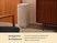 Caraway slim light-colored trash can beside a wooden cabinet.