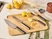 Caraway kitchen knives with dark handles arranged on a wooden cutting board with lemons.