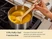 Hand stirring yellow soup in a stainless steel sauce pan with a wooden ladle.